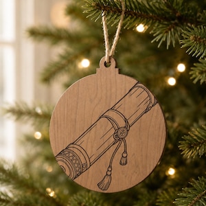 May include: A round, wooden Christmas ornament with a scroll design. The ornament is light brown with a dark brown scroll illustration. A jute string is attached for hanging. The ornament is hanging on a Christmas tree.