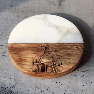 May include: A round coaster with a half-and-half design. The top half is white with a marble-like pattern, and the bottom half is wood-grained with a detailed etched image of a kiln, trees, and mountains. The coaster is approximately 4 inches in diameter.