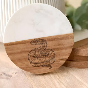 a round wooden coaster with a detailed engraved snake design on it.