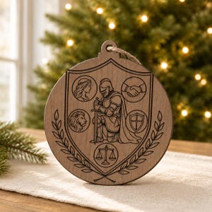 May include: A round, wooden Christmas ornament with a shield design. The shield features a knight, a lion, a woman, a handshake, a shield, and scales. The ornament has a natural wood grain and a jute string for hanging.