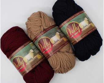 May include: Three skeins of yarn in burgundy, beige, and navy blue. Each skein has a label that reads "Dolly 100% Lana" with a sheep illustration.