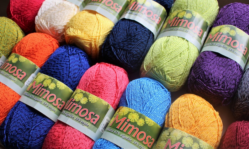 May include: A collection of colourful yarn skeins with the label "Mimosa" and the text "62% algod&oacute;n, 38% rayon".