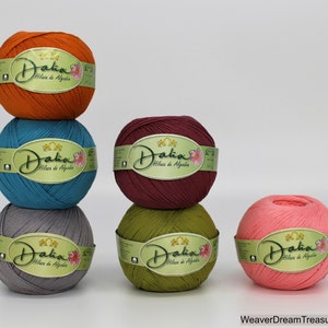 May include: Six balls of yarn in various colors, including orange, teal, gray, green, and pink. Each ball has a label that reads "Dalia Hilaza de Algodon".