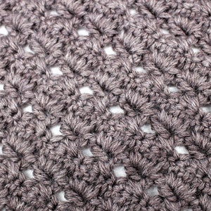 May include: Close-up of a crocheted fabric with a textured, open-weave pattern. The fabric is a dark brown color.