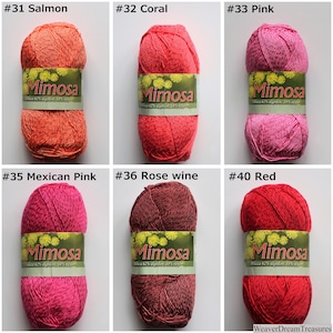 May include: Six balls of Mimosa yarn in various shades of pink, red, and orange. The yarn is labelled with the brand name "Mimosa" and the colour number. The colours are #31 Salmon, #32 Coral, #33 Pink, #35 Mexican Pink, #36 Rose wine, and #40 Red.