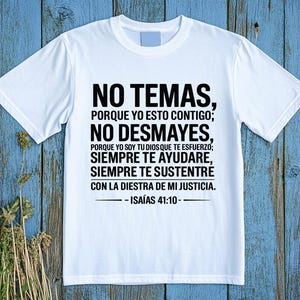 May include: A white t-shirt with black text. The text reads "NO TEMAS, PORQUE YO ESTO CONTIGO; NO DESMAYES, PORQUE YO SOY TU DIOS QUE TE ESFUERZO; SIEMPRE TE AYUDARE, SIEMPRE TE SUSTENTRE CON LA DIESTRA DE MI JUSTICIA. - ISAÍAS 41:10-".