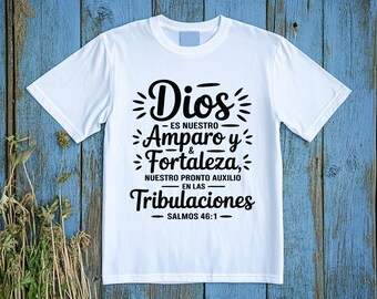May include: White t-shirt with a black graphic design. The design includes the word "Dios" above "Es nuestro Amparo y Fortaleza, nuestro pronto auxilio en las Tribulaciones" and "Salmos 46:1".