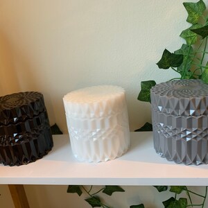 May include: Three decorative candle jars with a geometric pattern. The jars are black, white, and grey.