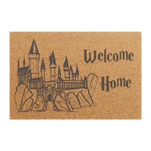 May include: A brown coir doormat with a black outline of Hogwarts castle and the text "Welcome Home".