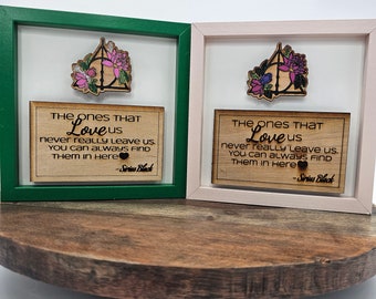 May include: Two framed wood signs with a green and pink frame. The signs feature a floral design with a black and white Deathly Hallows symbol. The text on the signs reads "The ones that Love us never really leave us. You can always find them in here - Sirius Black".