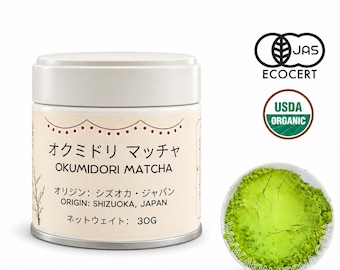 May include: A cylindrical white tin of Okumidori Matcha powder with a label featuring Japanese and English text, including "Origin: Shizuoka, Japan" and "Net Weight: 30g." Next to the tin is a small white bowl filled with vibrant green matcha powder.