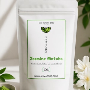 May include: White pouch of Jasmine Matcha powder. The label features green text and a green border with the text "AKI MATCHA 抹茶" and "Jasmine Matcha". The pouch contains 100g of product. The website address is www.akimatcha.com.