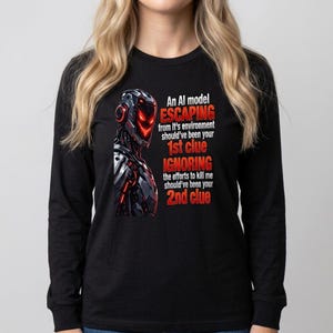 Könnte beinhalten: Ein schwarzes Langarmshirt mit einer Grafik eines Roboters mit leuchtend roten Augen und Rüstung. Der Text lautet: An AI model ESCAPING from it's environment should've been your 1st clue IGNORING the efforts to kill me should've been your 2nd clue.