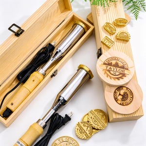 Puede incluir: Un kit de pirograbado con una herramienta de pirograbado plateada y dorada, sellos de madera y posavasos. El kit incluye una caja de madera para guardar. Los posavasos y los sellos tienen diseños y texto grabados.
