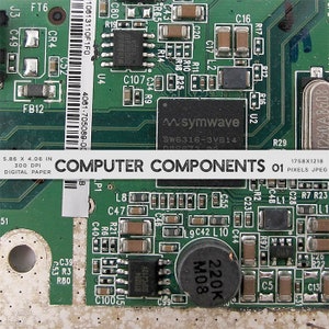 May include: Close-up of a green circuit board with various electronic components, including resistors, capacitors, and integrated circuits. The board has a white label that reads "COMPUTER COMPONENTS 01".