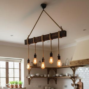 Può includere: Una lampada a sospensione rettangolare in legno scuro, appesa a corde spesse, dotata di cinque lampadine in stile Edison. L'apparecchio è posizionato sopra una grande isola cucina in legno con tre sgabelli dotati di sedute intrecciate.
