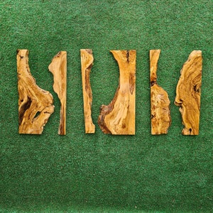 May include: Five pieces of wood with a natural wood grain pattern and irregular shapes. The wood is light brown and has a rustic appearance.