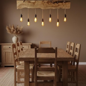 May include: A rustic dining room set featuring a wooden table and chairs with woven seats. Above the table hangs a unique light fixture made from a wooden beam with exposed light bulbs. The room has a warm, inviting atmosphere with neutral tones.