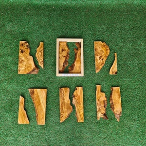 May include: Seven pieces of wood with a natural wood grain pattern, arranged on a green surface. The pieces are various shapes and sizes, and some have a rough, unfinished edge. The pieces are likely for a woodworking project or craft.