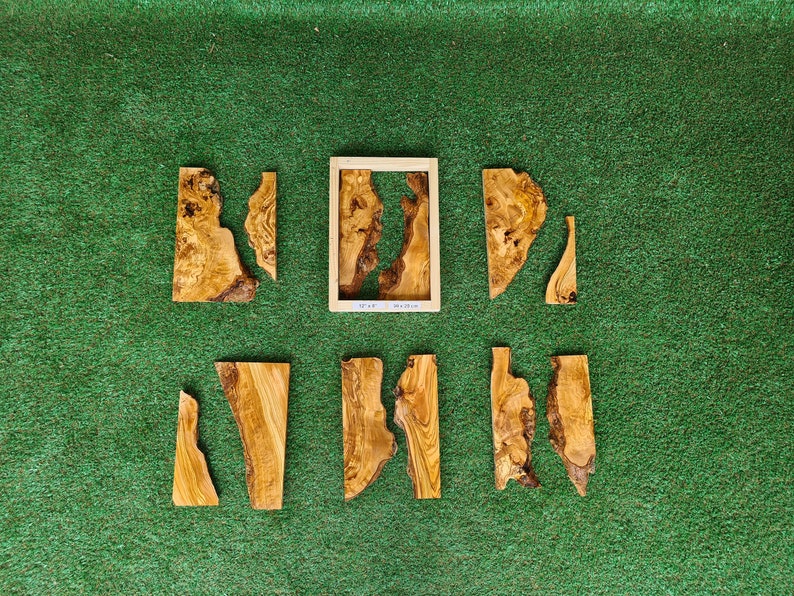 May include: Seven pieces of wood with a natural wood grain pattern, arranged on a green surface. The pieces are various shapes and sizes, and some have a rough, unfinished edge. The pieces are likely for a woodworking project or craft.