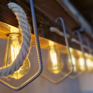 Puede incluir: Una l&aacute;mpara de madera r&uacute;stica con bombillas expuestas y detalles de cuerda. La l&aacute;mpara tiene una est&eacute;tica c&aacute;lida y acogedora y es perfecta para a&ntilde;adir un toque de encanto r&uacute;stico a cualquier espacio.