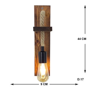 May include: A wall-mounted light fixture featuring a dark brown stained wooden backplate with a small shelf, a thick beige rope cord, and a black metal socket holding a glowing Edison-style light bulb. The fixture measures 44 cm by 9 cm by 17 cm.
