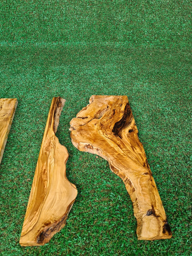 May include: Two pieces of natural wood with a unique grain pattern. The wood is light brown with darker brown streaks. The wood is on a green artificial grass background.