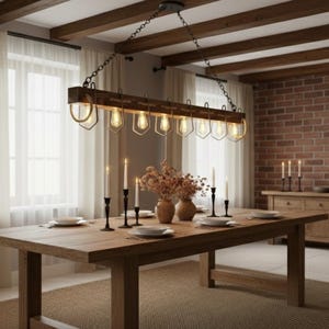 May include: A dining room scene featuring a large wooden table set for a meal. Above the table hangs a rustic chandelier with exposed light bulbs. The room has a brick wall, a fireplace, and neutral-colored curtains.