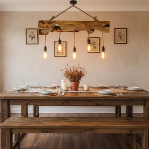 May include: A rustic dining room setup featuring a large wooden table and bench. Above, a unique light fixture made from a wooden beam hangs with Edison-style bulbs. The room is decorated with framed art and a centerpiece.