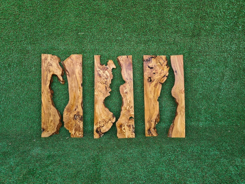 Puede incluir: Cinco piezas de madera de color natural, marr&oacute;n y marr&oacute;n claro. La madera tiene una forma org&aacute;nica &uacute;nica con un borde ondulado e irregular. Las piezas de madera est&aacute;n dispuestas en fila sobre una superficie verde.