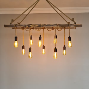 K&ouml;nnte beinhalten: Ein rustikaler Holz-Kronleuchter mit einem Seil-Design und mehreren Edison-Gl&uuml;hbirnen. Der Kronleuchter h&auml;ngt von der Decke und die Gl&uuml;hbirnen sind eingeschaltet.