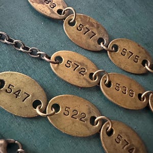 May include: A chain of oval brass tags with numbers 577, 575, 572, 539, 547, 522, and 574 printed on them.