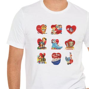 May include: White t-shirt with nine vintage Valentine's Day cards printed on the front. The cards feature various illustrations, including an owl, a boy and girl, a cat, a train, popcorn, and a chicken. The cards are all in red, pink, and blue colors.