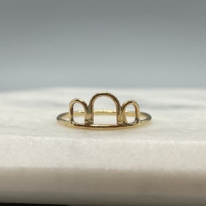 May include: A gold ring with a unique design featuring three arches. The ring is simple and delicate, making it a great everyday accessory.