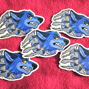 May include: Five stickers featuring a blue wolf with an angry expression. The wolf's head and shoulders are visible, with gray claws tearing through the design. The stickers are on a pink background.