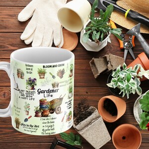 May include: White ceramic mug with a green, brown, and yellow design featuring gardening tools, plants, and the text "Gardener Life". The mug is surrounded by gardening tools, plants, and soil.