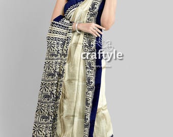 May include: A cream-colored saree with a navy blue border and accents. The saree features a detailed black and white pattern along the border and on the draped portion. The design includes geometric shapes and animal motifs. The text "craftyle" is visible.