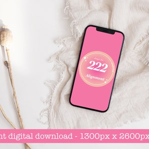May include: A pink phone screen with a white circle containing the text "Angel No. 222 Alignment" in a pink and orange gradient. The phone is on a white surface with a beige fabric.