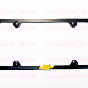 May include: Black license plate frame with a yellow and black Chevrolet logo. The frame has four black screw covers and is designed to fit a standard U.S. license plate.