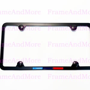 May include: Black license plate frame with four black screw caps. The frame has a blue, dark blue, and red stripe design at the bottom. The text "FrameAndMore" is visible in the background.