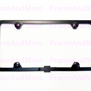 May include: Black license plate frame with a Chevrolet logo at the bottom center. The frame has rounded corners and four black screw covers. The text "FrameAndMore" is visible in the background.