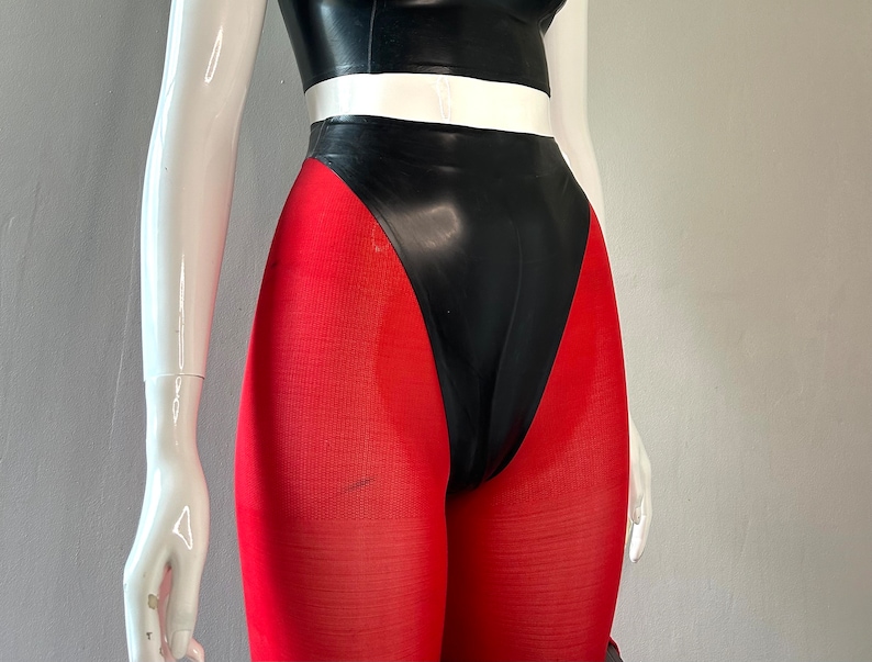May include: A black latex bodysuit with a white stripe at the waist and red leggings.