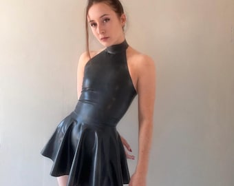 May include: A black halter dress with a flared skirt. The dress is made of a shiny material and has a high neckline. The dress is sleeveless and the skirt flares out from the waist. The dress is worn by a person.