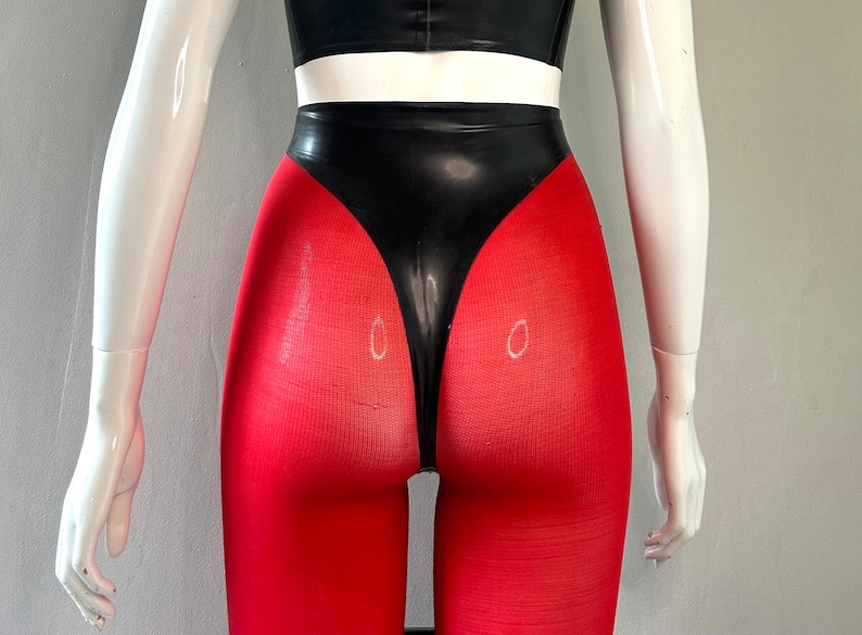 May include: A black and red latex bodysuit with a high-waisted, form-fitting design. The bodysuit features a black latex panel at the front and red fabric on the legs.