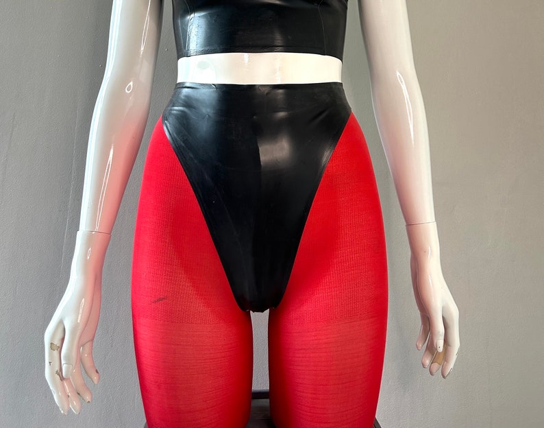 May include: A black latex high-waisted swimsuit with a white waistband and red tights.