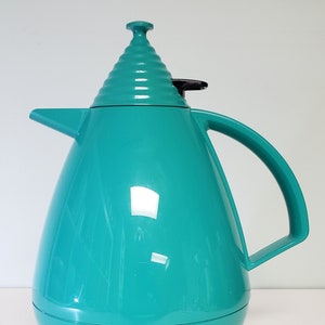 May include: A teal blue thermal carafe with a black lid and handle. The carafe has a unique, rounded, teardrop shape.