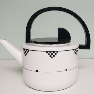May include: White enamel teapot with a black geometric design and a black handle. The teapot has a black lid with a small black knob.