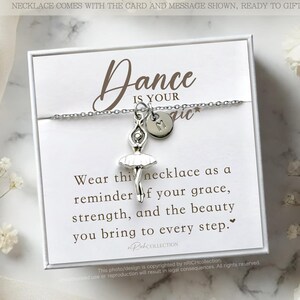 May include: A white card with a silver necklace featuring a ballerina charm and a letter charm. The card reads "Dance is your magic" and includes a message about grace, strength, and beauty.