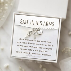 May include: A silver necklace with a cross, angel wing, and heart charm. The necklace comes in a white box with a message that reads "Safe in His Arms. Gone from earth, but never from your heart. Held in the arms of Jesus, where pain ends and peace begins. Forever safe in His embrace - Loved, missed, and never forgotten."