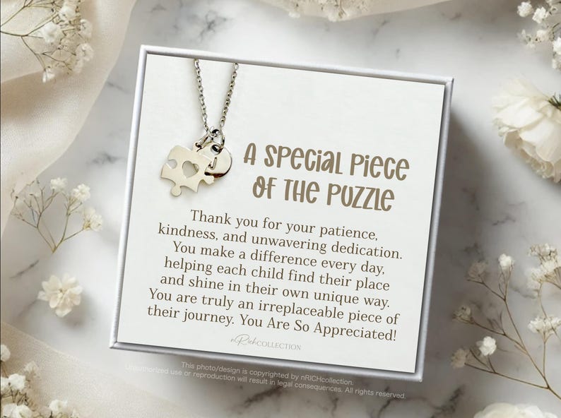 May include: A silver puzzle piece necklace with a heart cutout on a white card with the text "A Special Piece of the Puzzle" and a message thanking someone for their patience, kindness, and dedication. The message says "You are truly an irreplaceable piece of their journey. You Are So Appreciated!"
